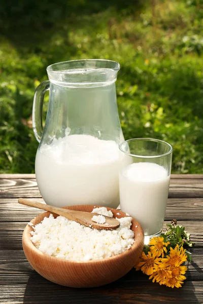 おいしい新鮮な牛乳とコテージチーズ木製のテーブルの屋外 — ストック写真