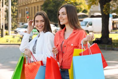 Şehir caddesinde alışveriş torbalarıyla güzel genç kadınlar