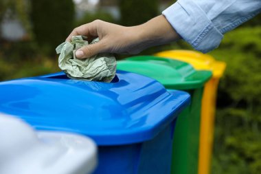 Woman throwing crumpled tissue into recycling bin outdoors, closeup clipart