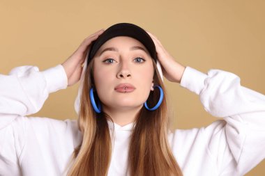 Bej arka planda dudak piercingli genç bir kadın.