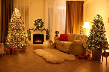 Noel ağaçları ve şöminesi olan şenlikli bir salon.