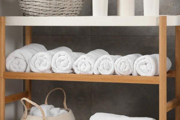 stock image Wooden shelf and wicker basket with soft terry towels in bathroom