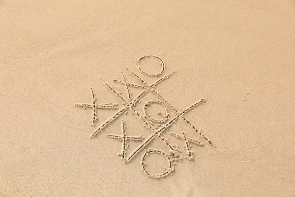 Stock image Tic tac toe game drawn on sandy beach, above view