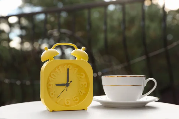Relógio Alarme Amarelo Xícara Com Bebida Quente Mesa Branca Manhã — Fotografia de Stock