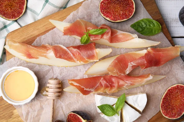 stock image Tasty melon, jamon and figs served on wooden board, flat lay