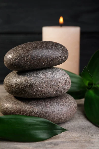 Gestapelte Wellness Steine Mit Bambusblättern Und Kerze Auf Holztisch Nahaufnahme — Stockfoto