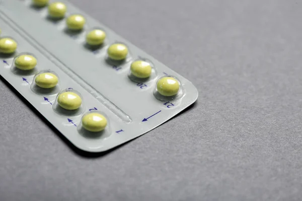 Birth control pills on grey background, closeup. Space for text