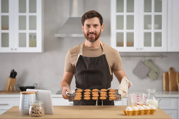 男人拿着格子在厨房里放着刚烤好的饼干 网上烹调课程 — 图库照片