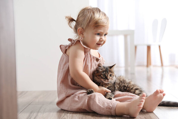 Cute little child with adorable pet on floor at home