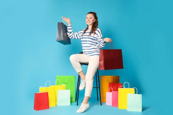 Açık Mavi Arka Planda Renkli Alışveriş Torbaları Taşıyan Mutlu Kadın — Stok fotoğraf