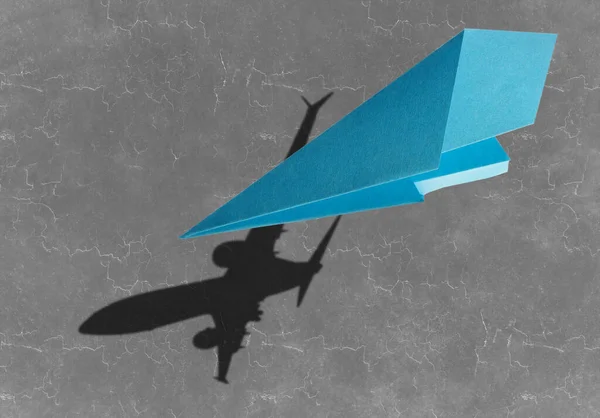 飞行的纸飞机和真正的飞机在沥青上的影子 — 图库照片