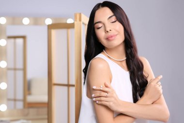 İçerde zarif inci takılar takan genç bir kadın, mesaj için yer var.