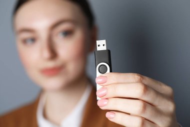 USB belleği gri arka planda tutan kadın, ele odaklan