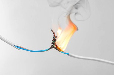 Gri arka planda iltihaplı beyaz kablo, yakın plan. Elektrik kısa devresi