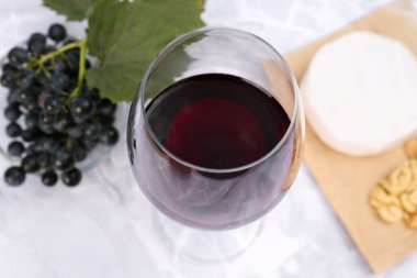 Beyaz mermer masada servis edilen kırmızı şarap ve atıştırmalıklar.