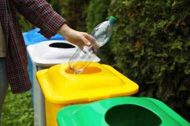 Kadın açık havada geri dönüşüm kutusu içine plastik şişe atma, kapatmak