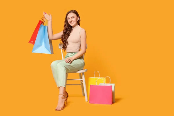 Turuncu Arka Planda Renkli Alışveriş Torbaları Tutan Mutlu Kadın — Stok fotoğraf