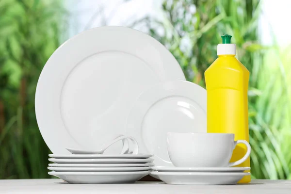 背景がぼやけている白いテーブルの上にきれいな食器と洗剤のセット — ストック写真