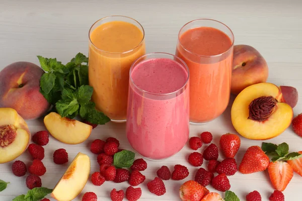 stock image Fresh colorful fruit smoothies and ingredients on white wooden table