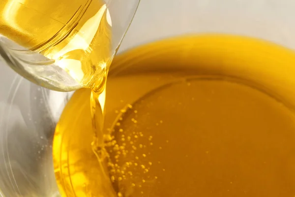 Pouring cooking oil from jug into bowl, closeup