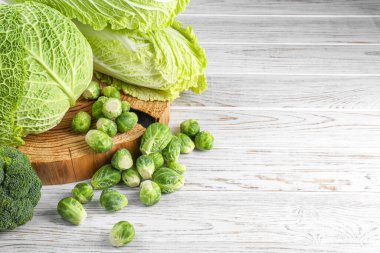 Different types of fresh cabbage on white wooden table, space for text clipart