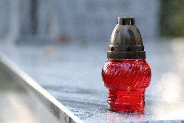 Açık havada granit mezar taşında yanan mum olan kırmızı mezar feneri, metin için alan