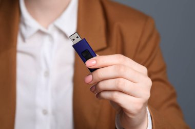 USB belleği gri arka planda tutan kadın, ele odaklan