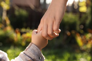 Annesinin elini tutan kız, yakın çekim görüntüsü.
