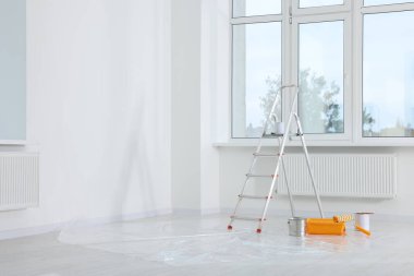 Boş odadaki pencerenin yanındaki merdiven ve boyama araçları, metin için boşluk