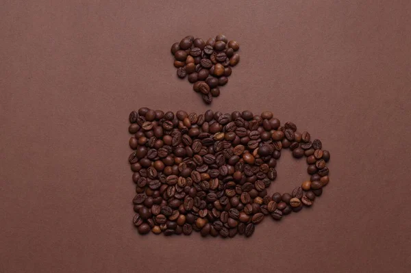 茶色の背景にコーヒー豆で作られたカップ トップビュー — ストック写真