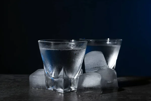 暗い背景に黒いテーブルの上に氷とショットグラスでウォッカ クローズアップ — ストック写真