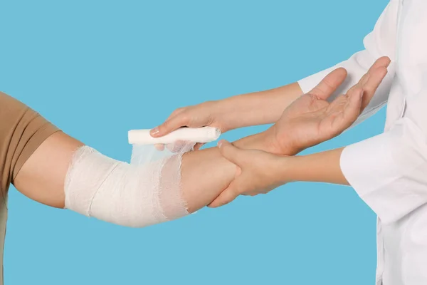 Läkare Applicera Bandage Patientens Arm Ljusblå Bakgrund Närbild — Stockfoto