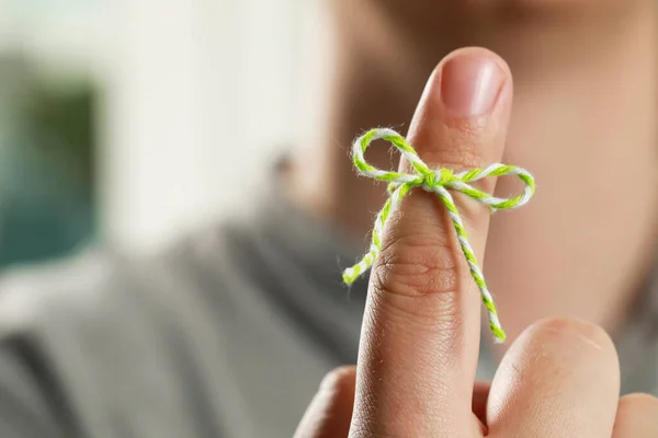 stock image Man showing index finger with tied bow as reminder against blurred background, focus on hand