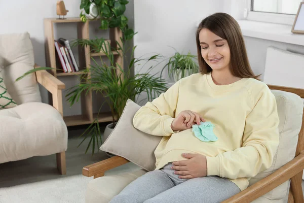 Glücklich Schwangere Frau Sitzt Auf Sessel Mit Babysocken Wohnzimmer — Stockfoto