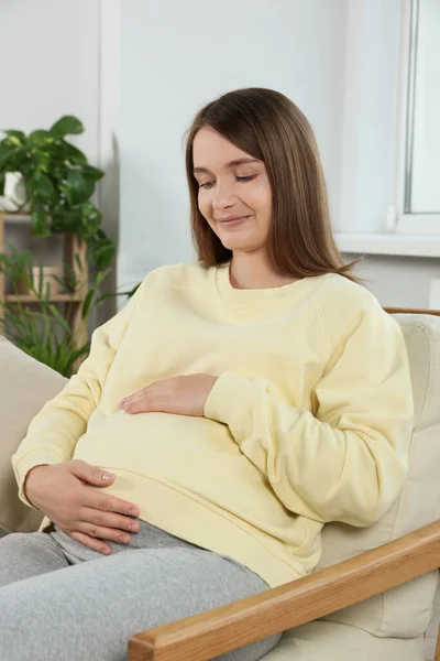 Lycklig Gravid Kvinna Sitter Fåtölj Och Vidrör Magen Vardagsrummet — Stockfoto