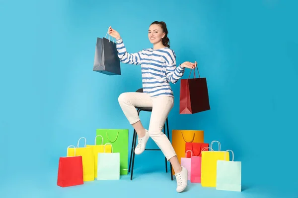 Mujer Feliz Sosteniendo Coloridas Bolsas Compras Taburete Contra Fondo Azul —  Fotos de Stock