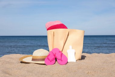 Deniz kenarında kumsal aksesuarlarıyla dolu bir yaz çantası.