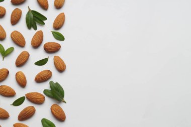 Lezzetli bademler ve beyaz arka planda taze yapraklar. Metin için boşluk