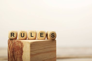 Word Rules made of cubes with letters on wooden block, space for text