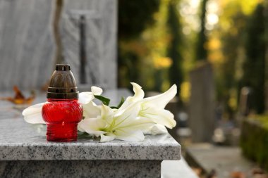 Açık havada granit mezar taşı üzerinde beyaz zambaklar ve mezar feneri, yazı için yer. Cenaze töreni.
