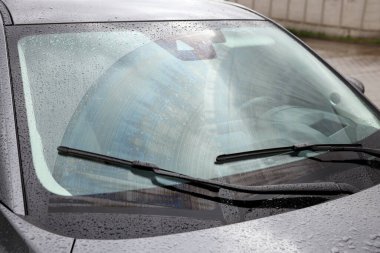 Araba silecekleri ön camdan su damlatıyor, yakın plan.