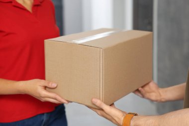 Kurye koridordaki müşteriye paket veriyor, yakın plan.