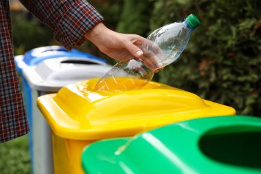 Kadın açık havada geri dönüşüm kutusu içine plastik şişe atma, kapatmak