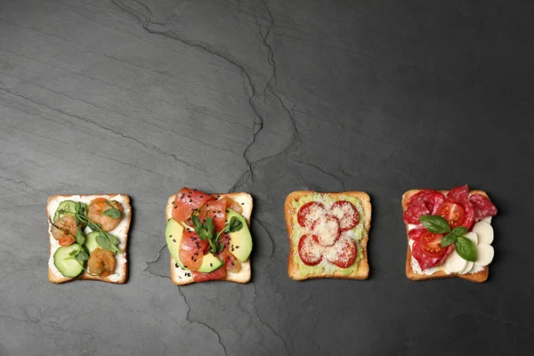 stock image Tasty toasts with different toppings on black table, flat lay. Space for text