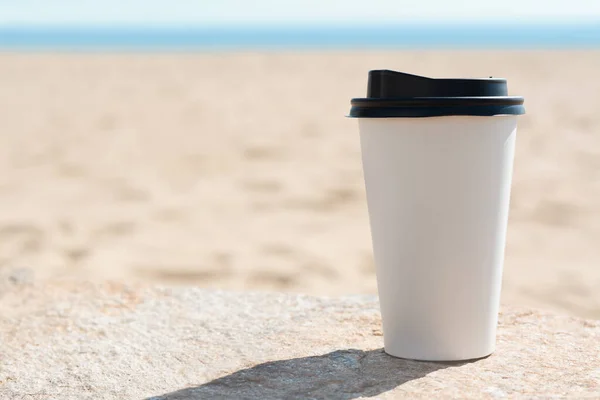 Takeaway coffee cup on beach, space for text