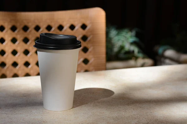 Takeaway coffee cup on beige table in cafe, space for text