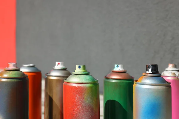 stock image Cans of different spray paints near wall outdoors, closeup