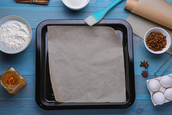 薄緑色の木製のテーブル フラットレイ上の羊皮紙 異なる成分とキッチンツールでパンを焼く — ストック写真
