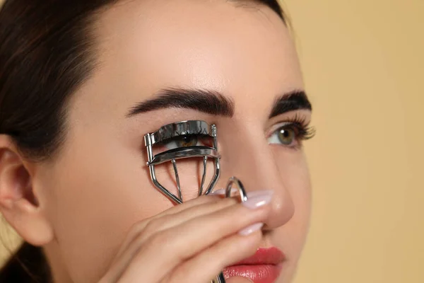 Woman Using Eyelash Curler Beige Background Closeup — Stockfoto