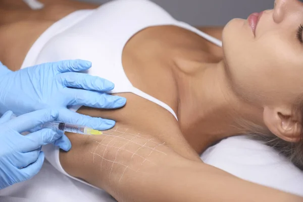 Young woman getting armpits injection in salon, closeup